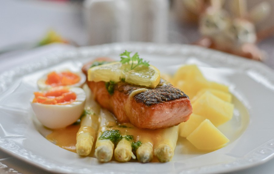 Gericht mit Fisch, Spargel, Eiern und Kartoffeln auf einem weissen Teller